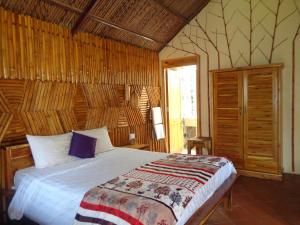 1 dormitorio con 1 cama y pared de madera en Ninila Fruit Farm Bungalow, en Phu Quoc