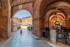 an archway in a building with people sitting at tables at La Terrasse de La Mandoune - T3 in Montauban