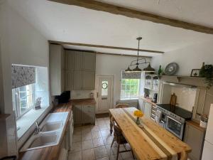 a kitchen with a wooden table in the middle of it at Riverside Cottage in Aycliffe +8 photos