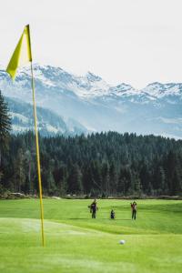 a group of people playing golf on a golf course at Hotel Alpenhof in Westendorf