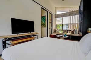 a bedroom with a white bed and a flat screen tv at OYO Life 92719 Rolling Hills Residence Karawang in Badami