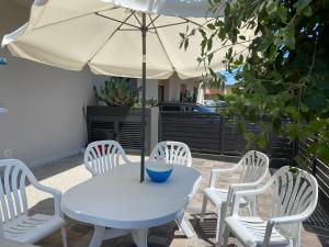 una mesa blanca y sillas con sombrilla en Casa Eva, en Bibione