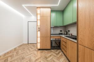 a kitchen with green cabinets and wooden floors at Volga Promenade Apartment in Durrës