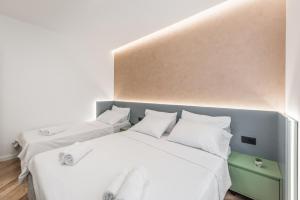 two beds in a room with white walls and wood floors at Volga Promenade Apartment in Durrës