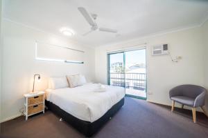 a bedroom with a bed and a chair and a window at Beachfront Unit on The Strand in Townsville