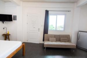 a bedroom with a bed and a chair and a window at Babosam Transient Dinihill in Boracay