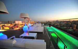 una terraza en la azotea con sofás blancos y luces verdes en Regency Palace Amman, en Amán