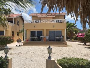 a large yellow house with a palm tree in front of it at Oceanfront apartments 18 & 19 - Lagun Blou Dive & Beach Resort, Curaçao in Lagun