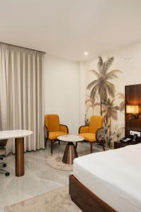 齐拉克普尔AVA Hotel Chandigarh Zirakpur的一间带床、椅子和桌子的酒店房间