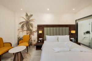 齐拉克普尔AVA Hotel Chandigarh Zirakpur的卧室里有一张白色的大床和两把橙色的椅子