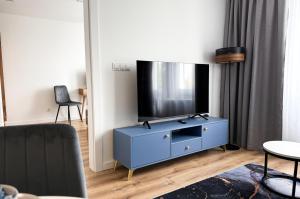 a living room with a tv on a blue cabinet at Apartamenty Piast Myślibórz in Myślibórz