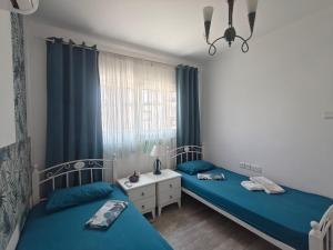 two beds in a bedroom with blue sheets and a window at Aquamarine in Voroklini +40 photos