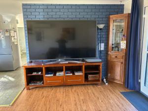 a flat screen tv on a wooden entertainment center at Jerilderie BNB - Pets Welcome - House in Jerilderie