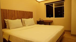 a bedroom with a large white bed with a window at Hotel Cikini in Jakarta
