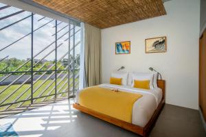 a bedroom with a bed and a large window at Atap Resort Canggu by Ini Vie Hospitality in Canggu