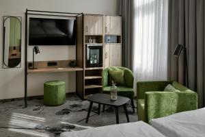 a hotel room with two green chairs and a tv at LIHO - einfach Lübeck in Lübeck