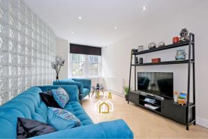 un salon avec un canapé bleu et une télévision dans l'établissement Bon Accord Square - SJA Stays - Modern 3 Bed Apartment, à Aberdeen