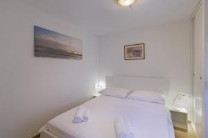 a bedroom with a white bed with slippers on it at Apartmani Spajić Duboka by aneo travel in Klek
