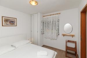 a white bedroom with a bed and a mirror at Apartmani Spajić Duboka by aneo travel in Klek