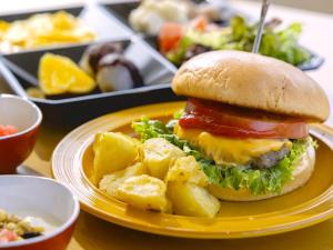 a yellow plate with a hamburger and potatoes on a table at KOKO HOTEL Kanazawa Station in Kanazawa