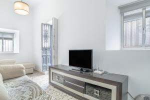 Una sala de estar con un televisor de pantalla plana sobre una chimenea. en Casa Pepa, en Barbate