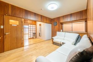 a living room with a white couch and wooden walls at 大和の宿 Minamibukuro in Nara