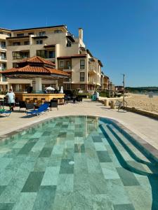 ein Pool neben einem Strand mit einem Gebäude in der Unterkunft Obzor Beach Resort in Obsor