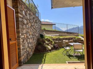 een patio met een stenen muur en een tafel en stoelen bij Casa Juliette in Bellano
