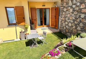 een tuin met een tafel en stoelen en een stenen muur bij Casa Juliette in Bellano