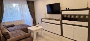 a living room with a couch and a tv at Korsako apartamentai in Šiauliai