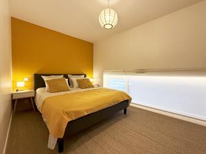una camera da letto con un letto con una parete gialla di Atelier Louis & Cie - Appartement classé 4 étoiles - 5 à 6 pers a Le Puy en Velay
