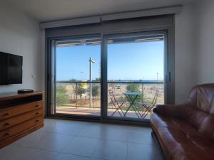Una sala de estar con un sofá y una puerta corrediza de vidrio. en Apartamento con vistas al mar y parking, en Palamós