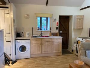 a kitchen with a sink and a washing machine at Bakers Mill Holiday Cottages in Beaminster
