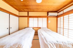 two beds in a room with two windows at 大和の宿 Minamibukuro in Nara
