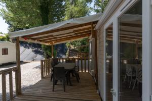 a wooden deck with a table and chairs on it at Les Rives d’Auzon confort 6 pers in Lavilledieu