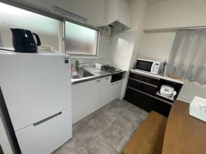 a small kitchen with a refrigerator and a microwave at フロンティアコート105号室 in Nagoya
