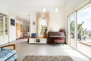 a living room with a piano and large windows at Rosh HaNikra Garden Villa Retreat by Sea N' Rent in Sulam Tsor