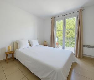 ein weißes Bett in einem Zimmer mit einem großen Fenster in der Unterkunft Proche Montpellier Maison sérénité et confort in Saint-Clément-de-Rivière