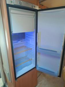 an empty refrigerator with its door open in a kitchen at Słoneczne Przyczepy Dębki in Dębki