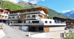 a large white building with mountains in the background at Apart Natur in Sölden
