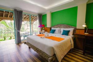 Un dormitorio con una cama grande con una pared verde. en Anggrek Sari Villa, en Tabanan 72 fotos más
