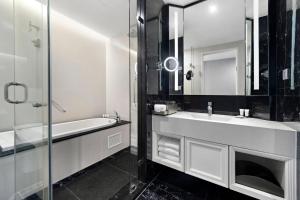 a bathroom with a sink and a tub and a mirror at Grande Centre Point Sukhumvit 55 Thong Lo in Bangkok