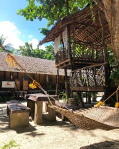 a hammock and a building with a tree at Amami Beachfront Bungalows & Villa in Puerto Galera