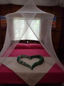 a heart pillow on a bed with a mosquito net at Amami Beachfront Bungalows & Villa in Puerto Galera +2 photos