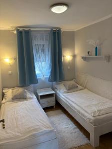 two beds in a small room with a window at Napsugár vendégház in Mezőkövesd