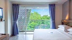 um quarto com uma cama e uma janela grande em Clarian Hotel Beach Patong em Patong Beach