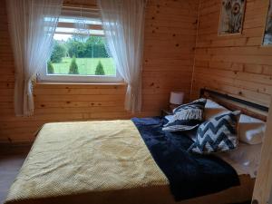 a bedroom with a bed with pillows and a window at Domki pod szybowiskiem in Lesko