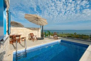 a swimming pool with a table and an umbrella at Villa Miri Melon in Privlaka