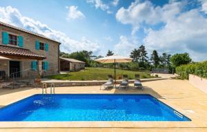 a pool with two chairs and an umbrella next to a house at Vila Azzura - Buje by Villas Guide in Buje