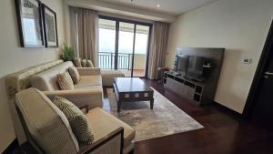 Stunning 1BR at Anantara Sea Views Palm Jumeirah في دبي: غرفة معيشة مع أريكة وتلفزيون